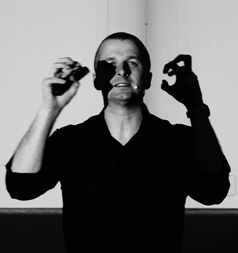 A photo of Mark standing on stage gesticulating